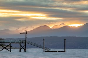 Winter Setting Sun at Hood Canal in Washington State with Boat Dock in foreground and Olympic Mountains in background